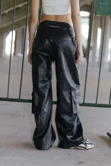 Pantalón cargo de ecocuero negro, de corte holgado y tiro medio-alto. Presenta bolsillos laterales tipo cargo y costuras visibles a lo largo de las piernas.