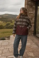 Campera de abrigo con diseño híbrido, presentando una parte superior a cuadros en tonos marrones y blancos, y una parte inferior acolchada en color bordó. Posee cuello alto, cierre frontal completo y diseño de corte amplio.