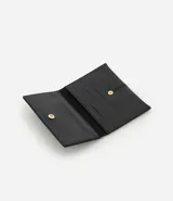 Billetera tipo sobre de tamaño pequeño, confeccionada en poliuretano con acabado barnizado brillante. Presenta un diseño minimalista con costuras verticales decorativas y cierre mediante botón a presión.