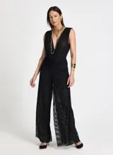 Pantalón de tiro alto con corte de pierna ancha y caída fluida. Confeccionado en tejido de punto con textura brillante y sutil transparencia, presenta una cinturilla ancha estructurada con un ligero fruncido bajo la misma y bajo recto.