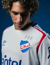 Camiseta de fútbol Umbro del Club Nacional de Football, modelo Home 2025, para hombre. Diseño blanco con detalles en azul y rojo en cuello y mangas. Incluye logo de Umbro, escudo del club y sponsor Antel en el frente.