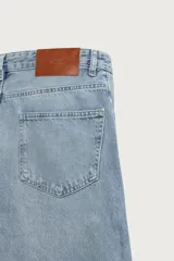 Jeans relaxed barrel fit confeccionados en denim de algodón color celeste con efecto lavado. Presentan tiro medio, corte amplio con forma curva que se estrecha hacia el tobillo, diseño de cinco bolsillos, detalle de pinza en las rodillas y cierre frontal con cremallera y botón.