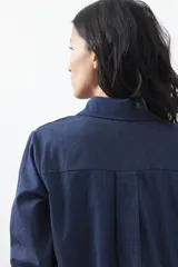 Camisa de manga larga en color azul oscuro con bordados florales en hilo blanco a lo largo de la botonadura frontal. Presenta cuello clásico y corte relajado.
