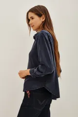 Camisa de corte amplio y holgado, confeccionada en viscosa con efecto lavado. Presenta detalles bordados en los hombros, cuello clásico, cierre frontal con botones y mangas largas con puños.