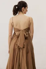 Vestido largo color beige con escote recto, tirantes finos y falda amplia con diseño drapeado.