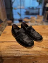 Mocasín de mujer en color negro, confeccionado en cuero con textura de pelo, diseño clásico con banda frontal y suela de taco bajo.
