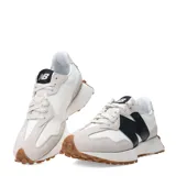 Championes urbanos New Balance modelo 327, con diseño retro inspirado en los años 70. Presentan una combinación de paneles de gamuza gris claro y base de nylon blanco, con el logo 'N' sobredimensionado en cuero sintético negro en el lateral. Incluyen una entresuela de espuma blanca y una suela de goma dentada que se extiende hacia el talón.