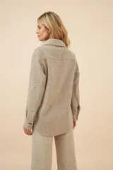 Camisa estilo leñador color beige con textura en espiga, de manga larga, con cuello clásico, cierre frontal con botones, dos bolsillos de parche con solapa abotonada en el pecho y puños abotonados. Confeccionada en lana fina sin teñir.