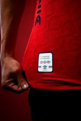 Camiseta de fútbol Umbro del Club Nacional de Football, modelo Away 1. Diseño principal en color rojo con cuello en V azul, detalles blancos en los hombros y puños blancos. Incluye el escudo del club, logo de Umbro y sponsors estampados.