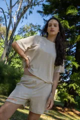 Conjunto color beige de waffle liviano, compuesto por una remera de mangas cortas y un short con cintura elástica y logo bordado en color naranja.