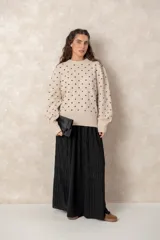 Buzo de punto color beige con estampado de lunares negros en relieve, cuello redondo y mangas largas abullonadas con puños acanalados.