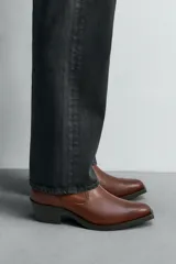 Bota de cuero color marrón, estilo cowboy, con caña corta, puntera en punta y tacón cubano.