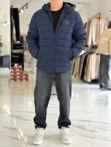 Campera puffer azul marino con capucha ajustable, cierre frontal y bolsillos laterales con cierre a presión. Cuenta con parche redondo con la inscripción "TURK" en el pecho.