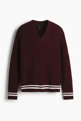 Buzo de punto acanalado en color bordó, con cuello en V y detalles de rayas blancas en contraste en los puños y el ruedo. Presenta un corte boxy que ofrece una silueta amplia y estructurada.
