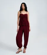 Pantalón estilo aladino color bordó, confeccionado en tejido crepé con textura. Presenta cintura elástica, corte holgado en las piernas y ruedo ajustado con lazo decorativo.