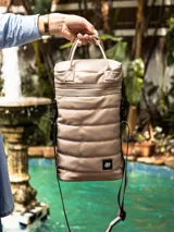 Bolso matero negro de cuero sintético con diseño capitoneado, correa larga regulable y doble asa corta.