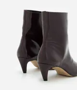 Bota de caña media Satinato, confeccionada en poliuretano con acabado brillante. Presenta diseño ajustado al tobillo, punta cuadrada y tacón fino de 6 cm. Incluye cierre lateral discreto.