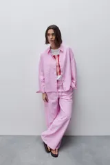 Pantalón de tiro alto con silueta amplia y caída fluida, confeccionado en tejido celeste con textura a rayas finas. Cuenta con cintura elástica con lazo de ajuste y bolsillos laterales.