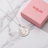 Dije circular de plata 925 con incrustación de nácar y silueta de niña grabada en el centro.