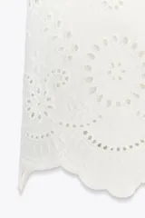 Falda pantalón corta de tiro alto color blanco con bordados florales perforados y forro interior. Cierre lateral con cremallera oculta.