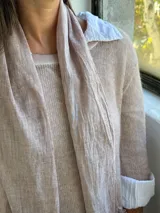 Sweater de punto rosa claro con diseño de capas, que incluye una camisa blanca debajo y un pañuelo a juego con detalles de encaje y flecos en el ruedo.