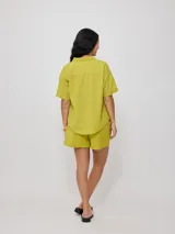 Camisa color verde lima, de manga corta, con bolsillo en el pecho y cierre con botones.