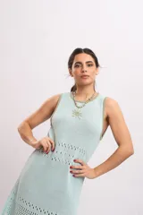 Vestido midi de punto color celeste con detalles en verde militar en el cuello y las sisas, sin mangas y con diseño calado en la parte inferior.