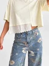 Jean wide leg de tiro alto con estampado de flores y hojas verdes, de corte amplio y cómodo.