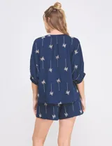 Blusa de rayón y poliéster color azul marino con bordados de palmeras en tono beige, cuello en V, mangas 3/4 holgadas con puño ajustado y diseño holgado de corte asimétrico.
