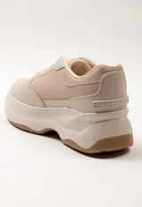 Zapatilla acordonada con diseño de varios cortes, colores y texturas. Plataforma irregular y bicolor de 5 cm de alto. Predominan los tonos blanco, beige y gris.