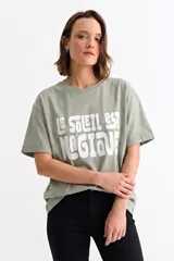 Remera de algodón color verde oliva con cuello redondo, mangas cortas y estampa frontal con la frase 'LE SOLEIL EST MAGIQUE' en letras blancas.