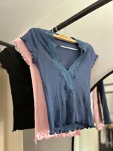 Remera corta de color verde claro con detalles de encaje en el escote y mangas cortas.