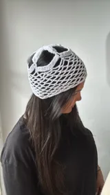 Gorro blanco de crochet con diseño de red y aberturas en la parte superior.