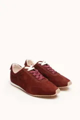Zapatilla de gamuza color bordó con cordones bicolores, interior de cuero vacuno y suela de caucho blanca y beige.