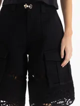 Bermuda de gabardina liviana color negro, de silueta recta y largo por arriba de la rodilla. Cuenta con bolsillos cargo laterales y detalle de encaje en el ruedo. Su acceso es mediante broches metálicos y cierre en bragueta.