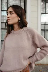 Buzo de lana color rosado, con cuello redondo, mangas largas y diseño holgado.