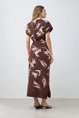Vestido midi marrón con estampado floral blanco, cuello mao, manga corta y lazo ajustable en la cintura.