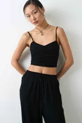Top negro confeccionado en una mezcla de viscosa y lino, con tirantes finos ajustables, escote en V y diseño fruncido en el centro del frente.