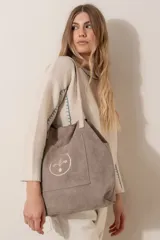 Bolso tipo tote bag de gamuza azul con asas de cuero marrón y bolsillo externo con logo bordado.