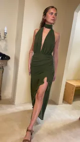 Vestido largo de microtul color verde militar, con escote profundo en V, cuello halter y detalle de choker incorporado. Falda cruzada con frunces laterales, tajo pronunciado con volados y transparencias.