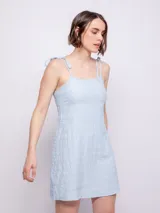 Vestido corto celeste con textura, tirantes finos y lazos en los hombros.