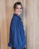 Sobrecamisa de pana color marrón oscuro, con cuello camisero, cierre frontal de botones y detalle de volado en el ruedo. Presenta mangas largas con puños y bolsillos frontales aplicados.