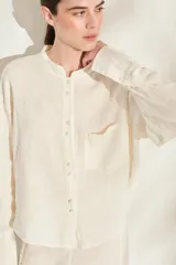 Camisa de lino italiano color beige, de corte holgado, con cuello mao, manga larga y bolsillo aplicado en el pecho.