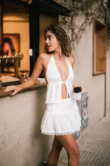 Top corto con estampado de cuadros vichy en blanco y negro, escote halter y lazo ajustable en el frente. El ruedo está decorado con encaje celeste.