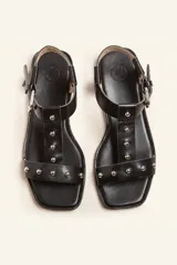 Sandalias negras de cuero con tiras finas, pulsera al tobillo con hebilla metálica y apliques de tachas plateadas.