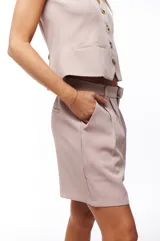 Short de vestir color rosa pálido, con pinzas delanteras, bolsillos laterales y cierre frontal con botón y cremallera.