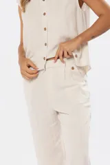 Pantalón confeccionado en mezcla de lino y viscosa, color beige, de corte recto. Cuenta con media cintura elastizada, bolsillos laterales y detalles de pinzas en el frente.