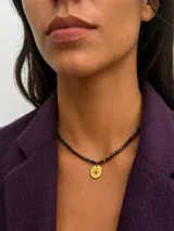 Collar de cuentas facetadas de piedras naturales multicolor con dije dorado ovalado en forma de sol con una piedra central.