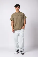 Remera de algodón peinado con efecto desgastado (snow wash), color gris oscuro. Presenta un estampado frontal con texto y un patrón de cuadros de carreras.