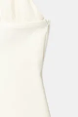 Top negro de cuello halter con escote en pico pronunciado. Presenta un cuerpo estructurado y una parte superior de tul plisado con detalle de lazada tipo foulard en el cuello. Incluye cierre lateral con cremallera oculta.